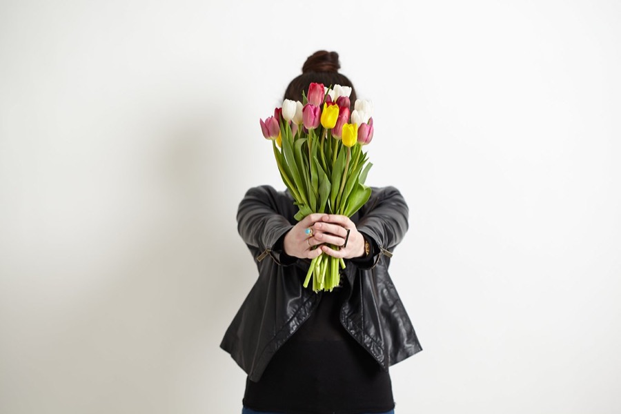 チューリップの花束を抱えて笑う人